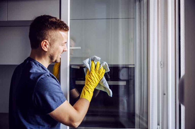 En man från bästa städfirman i Norrköping håller på att städa en glasdörr i ett kök.