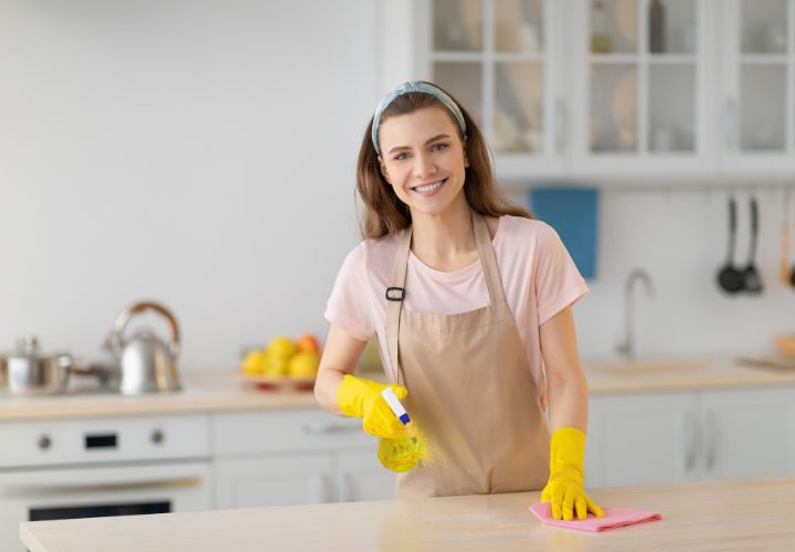 En kvinna som bär handskar och städar en köksbänk i Norrköping.