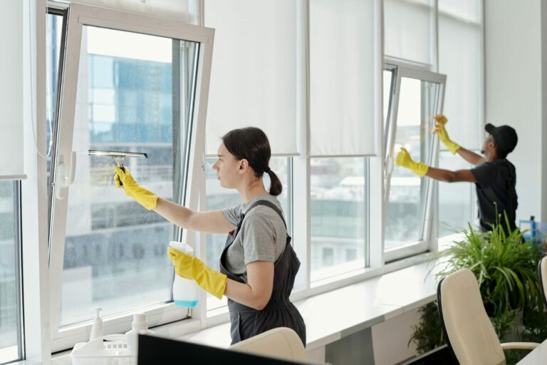 En kvinna som putsar fönster med en sprayflaska.